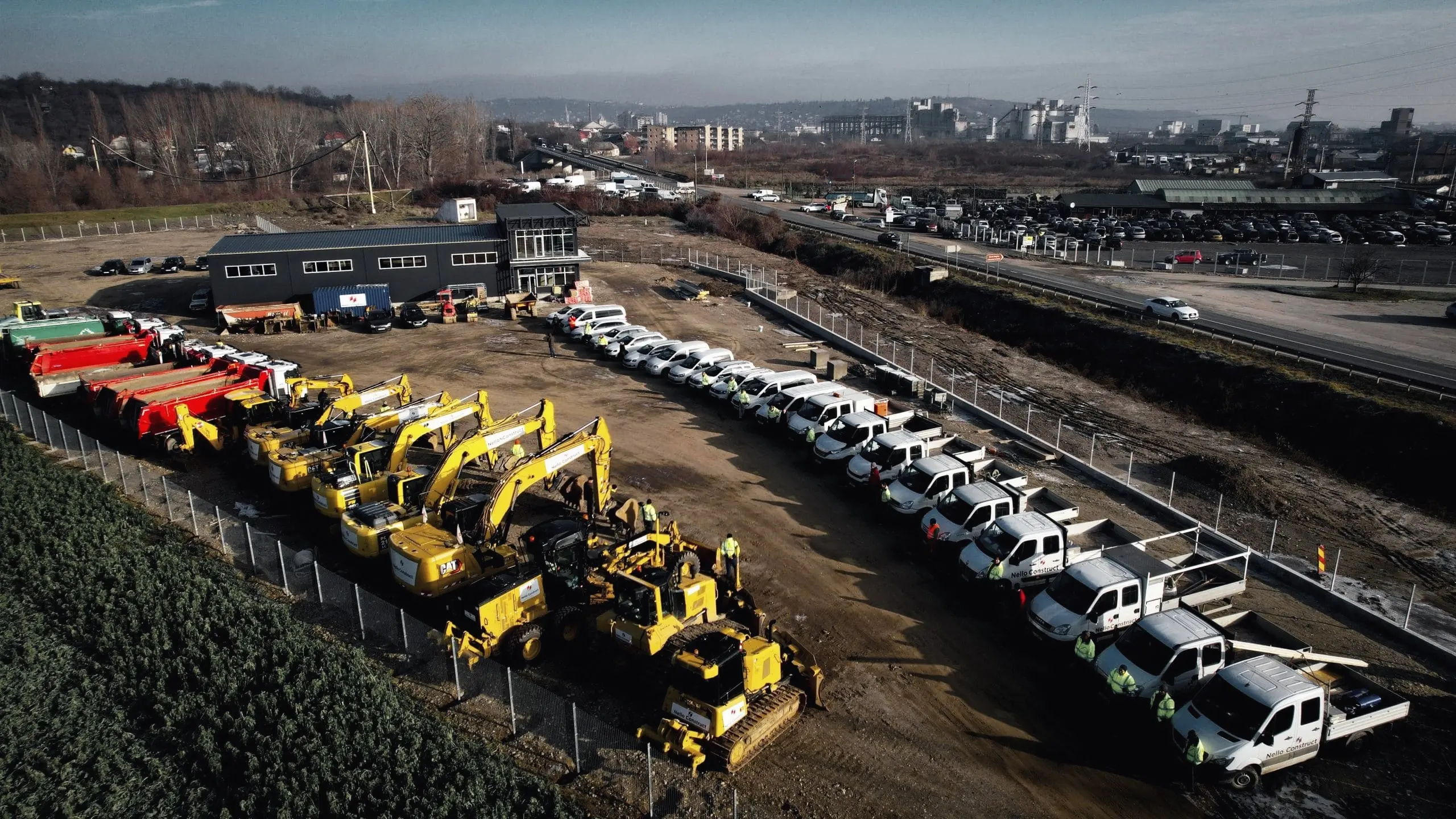 Flota Nello Construct: utilaje galbene și camioane aliniate, văzute din dronă